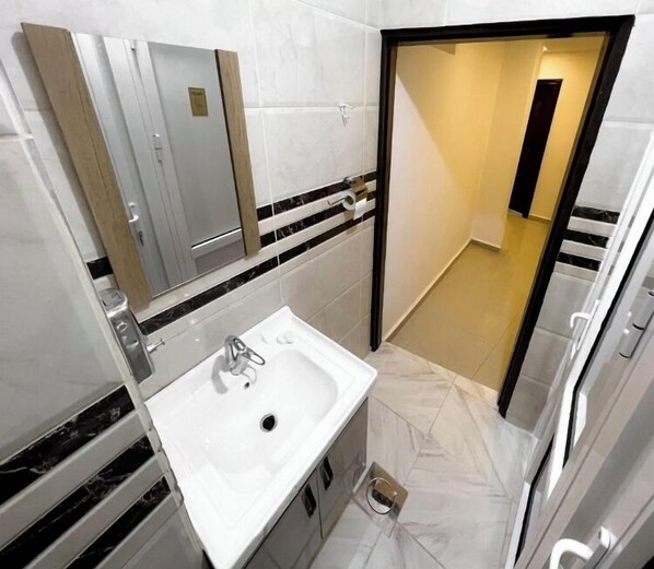 Une salle de bain moderne avec un lavabo blanc, un miroir et des toilettes.