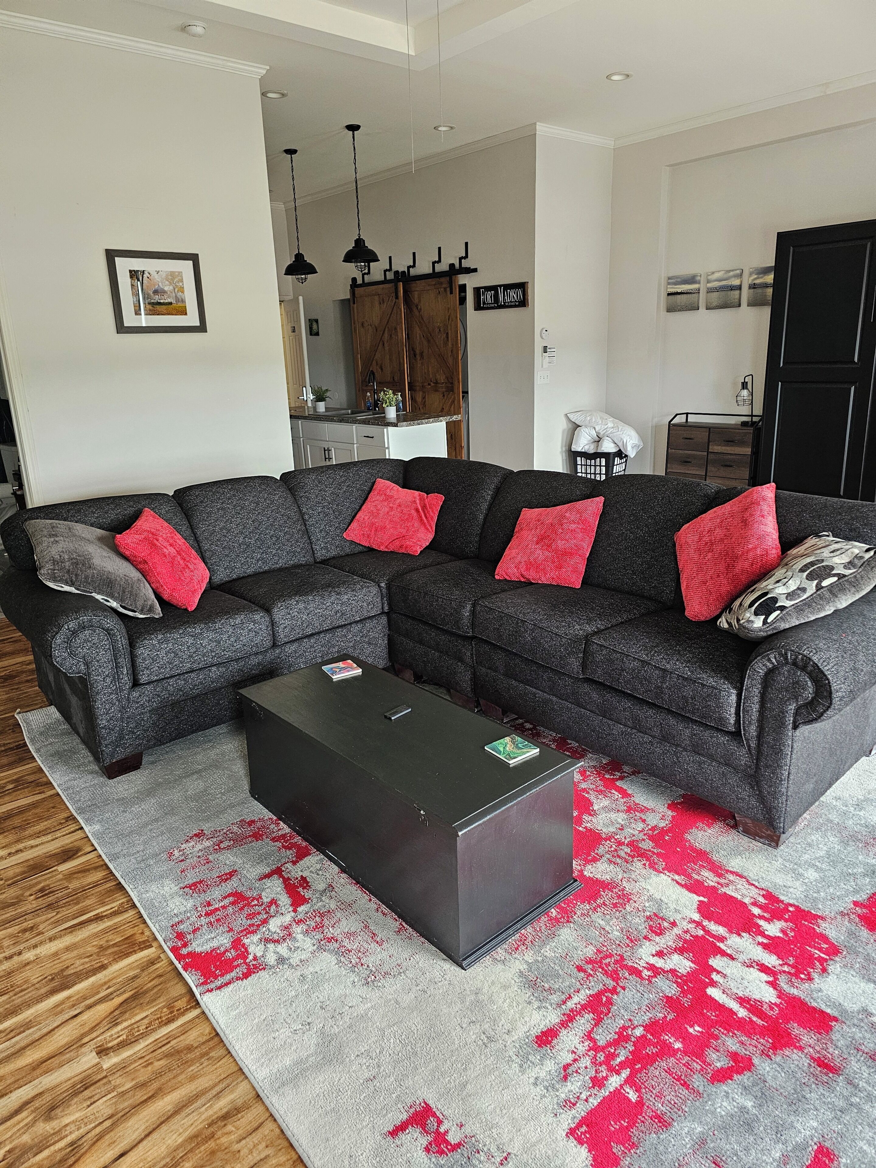 Un salon moderne avec un canapé d’angle, une table basse et une cuisine en arrière-plan.