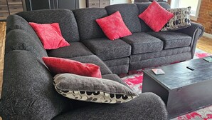 Ein modernes Wohnzimmer mit einem Ecksofa, einem Couchtisch und einer Ziegelwand.