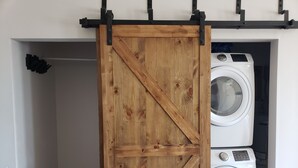 Eine hölzerne Schiebetür in einem Waschraum, in dem zwei Waschmaschinen übereinander stehen.