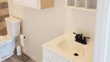 A bathroom with a toilet, sink, and cabinets.
