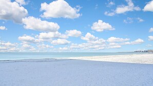 A beach with a clear sky and distant buildings. - SEA WINDS 1201  
Beach Front Getaway with spectacular views of the Gulf! (Marco Island)