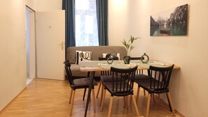 A dining area with a table, chairs, a sofa, and a plant. - 3 Bedrooms - 72sqm - 15 Min. City Center (Vienna)