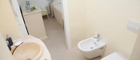 Un baño con tocador de madera, un bidé y un inodoro.