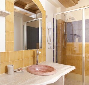 Bathroom features a large mirror, sink, and glass-enclosed shower.