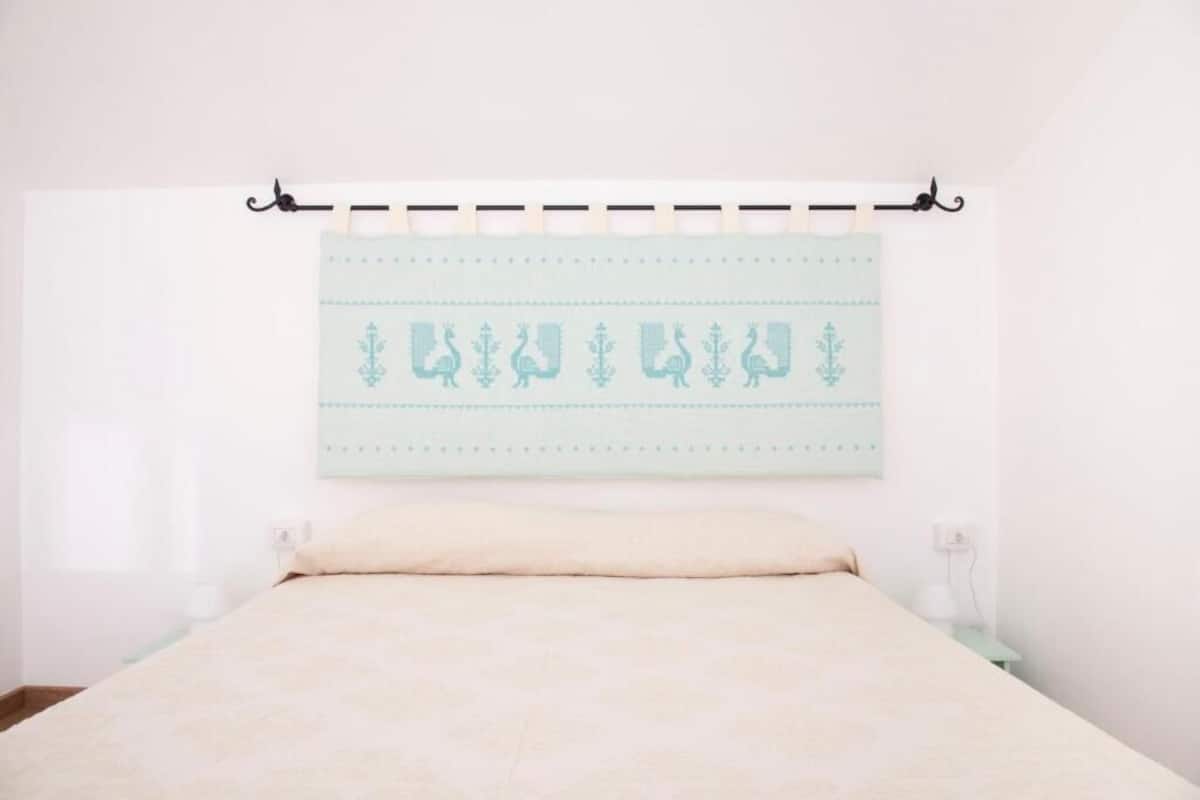 Een slaapkamer met een bed, nachtkastje en een kunstwerk aan de wand.