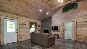 A log cabin interior with a stone fireplace, a television, and a sofa. - Bear cabin. This modern log cabin with HOT TUB is a large studio with a spectacular king size bed! (Tellico Plains)