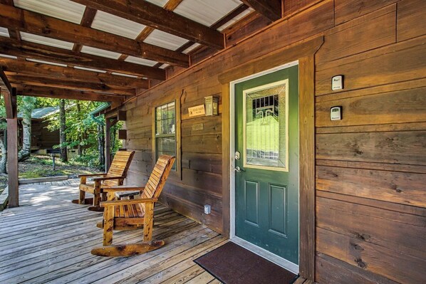 Eine Holzhütte mit grüner Tür, einer Veranda mit Holzstühlen und einer Holzterrasse.