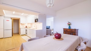 A modern kitchen with white cabinets, a built-in oven, and a dining area with a table set for two.