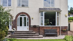 A two-story house with a front door, a bay window, and a bench outside. - 3 bedroom accommodation in Keswick (Keswick)