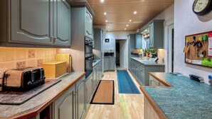 A modern kitchen with grey cabinets, a wooden ceiling, and a blue countertop. - 3 bedroom accommodation in Keswick (Keswick)