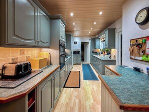 A modern kitchen with grey cabinets, a wooden ceiling, and a blue countertop.