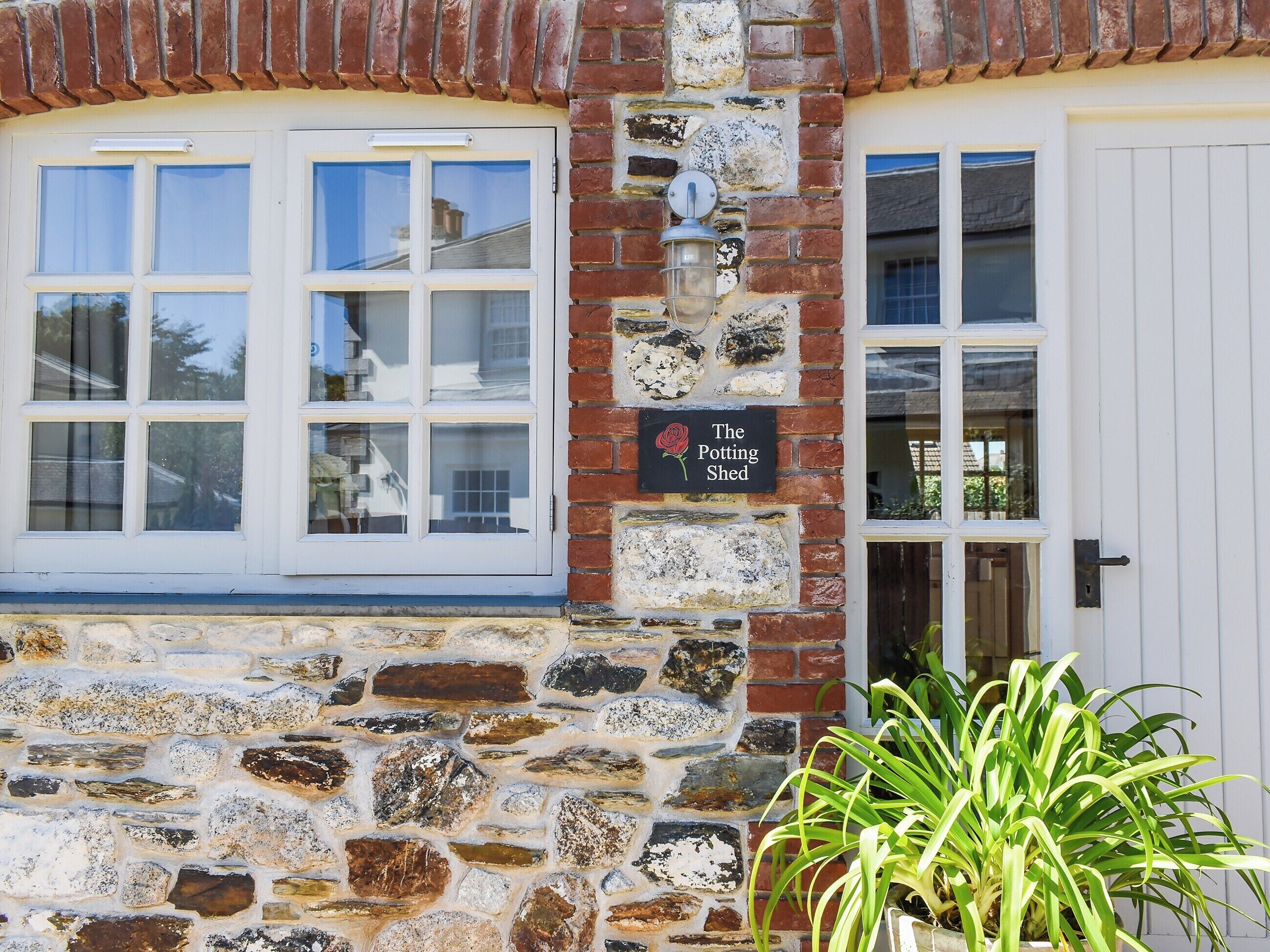 Un bâtiment en pierre sur lequel est apposée une enseigne indiquant : « The Potting Shed ».