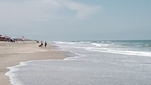 Una playa con una amplia orilla arenosa y olas suaves.