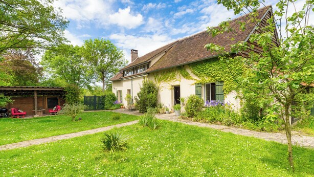 A house with a garden, a barbecue area, and a covered patio.