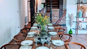 A dining area with a long wooden table set for six, surrounded by wooden chairs.