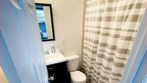 Un baño con lavamanos blanco, inodoro y cortina de ducha a rayas.
