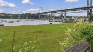 Un ponte sopra un fiume, con barche, aree verdi e vegetazione sullo sfondo.