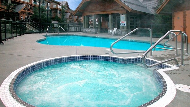 A hot tub with a tiled edge, surrounded by a concrete deck. - Cozy fully renovated townhome,free parking. Minutes away from Whistler Village. (Whistler)