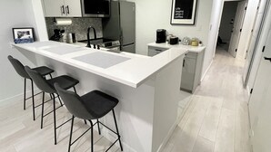 A modern kitchen with a central island, bar stools, a microwave, and a refrigerator. - Cozy fully renovated townhome,free parking. Minutes away from Whistler Village. (Whistler)