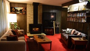 Una sala de estar acogedora con chimenea, sofás de cuero, una mesa de centro y una estantería llena de libros.