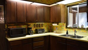 Una cocina con armarios de madera, microondas, tostadora y pileta.