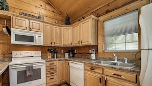 Una cocina con armarios de madera, microondas, estufa, lavavajillas y un lavabo.