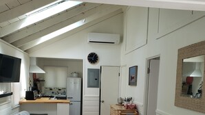 A compact living space with a kitchenette, a dining area, and a seating area with a sofa and chairs.