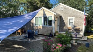 A house with a covered patio, outdoor seating, and a garden with flowers.