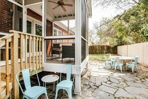 A covered patio with a wooden deck, outdoor seating, and a screened area.