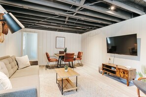 A modern living room with a dining area, a flat-screen TV, and a ceiling with exposed beams. - Lewis Mtn Midterm: 31+ days, Walk to UVA (Charlottesville)