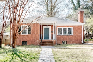 A single-story brick house with a front door, a small porch, and a visible number '2026' on the door. - Lewis Mtn Midterm: 31+ days, Walk to UVA (Charlottesville)