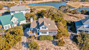 A large house with multiple sections, a pond, and a golf course in the background. - Newly Remodeled, 5 BR, across from South Beach.  Shoals & BHI Clubs available (Bald Head Island)