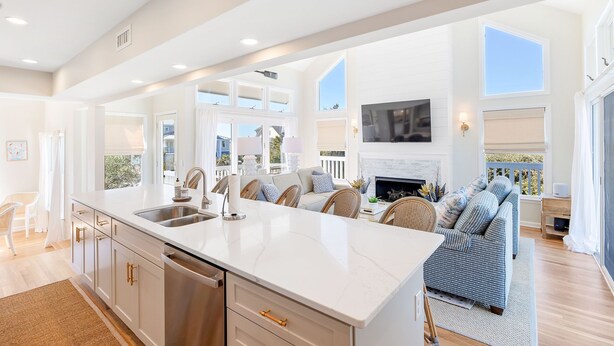 A spacious kitchen with a large island, a dining area with a sofa, and a fireplace. - Newly Remodeled, 5 BR, across from South Beach.  Shoals & BHI Clubs available (Bald Head Island)