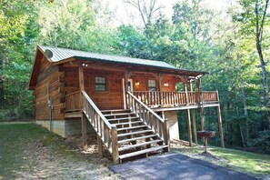 A log cabin with a porch and stairs leading to the entrance. - Angler cabin. This modern private studio Cabin with HOT TUB is tucked away in a wooded cove. (Tellico Plains)