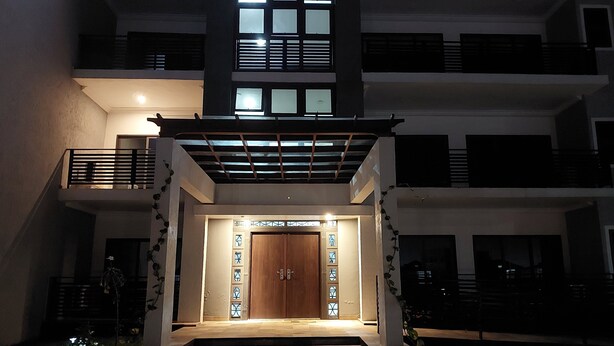 A modern building with a wooden door, a staircase leading to the entrance, and a balcony with railings. - 2,3 Ensuite Bedrooms Luxury Staycation and Vacation apartments (Kasoa)