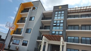 A multi-story building with balconies, a basketball hoop, and a sign reading "OCTOBER APARTMENTS". - 2,3 Ensuite Bedrooms Luxury Staycation and Vacation apartments (Kasoa)