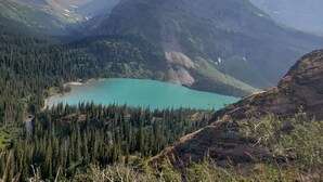 Un paisaje montañoso con un lago turquesa rodeado de densos bosques y picos escarpados.
