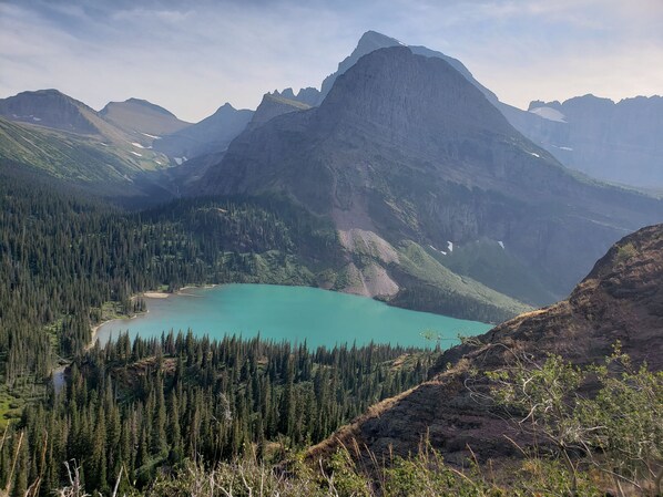 Berglandschap met een turquoise meer, omgeven door dichte bossen en ruige toppen.