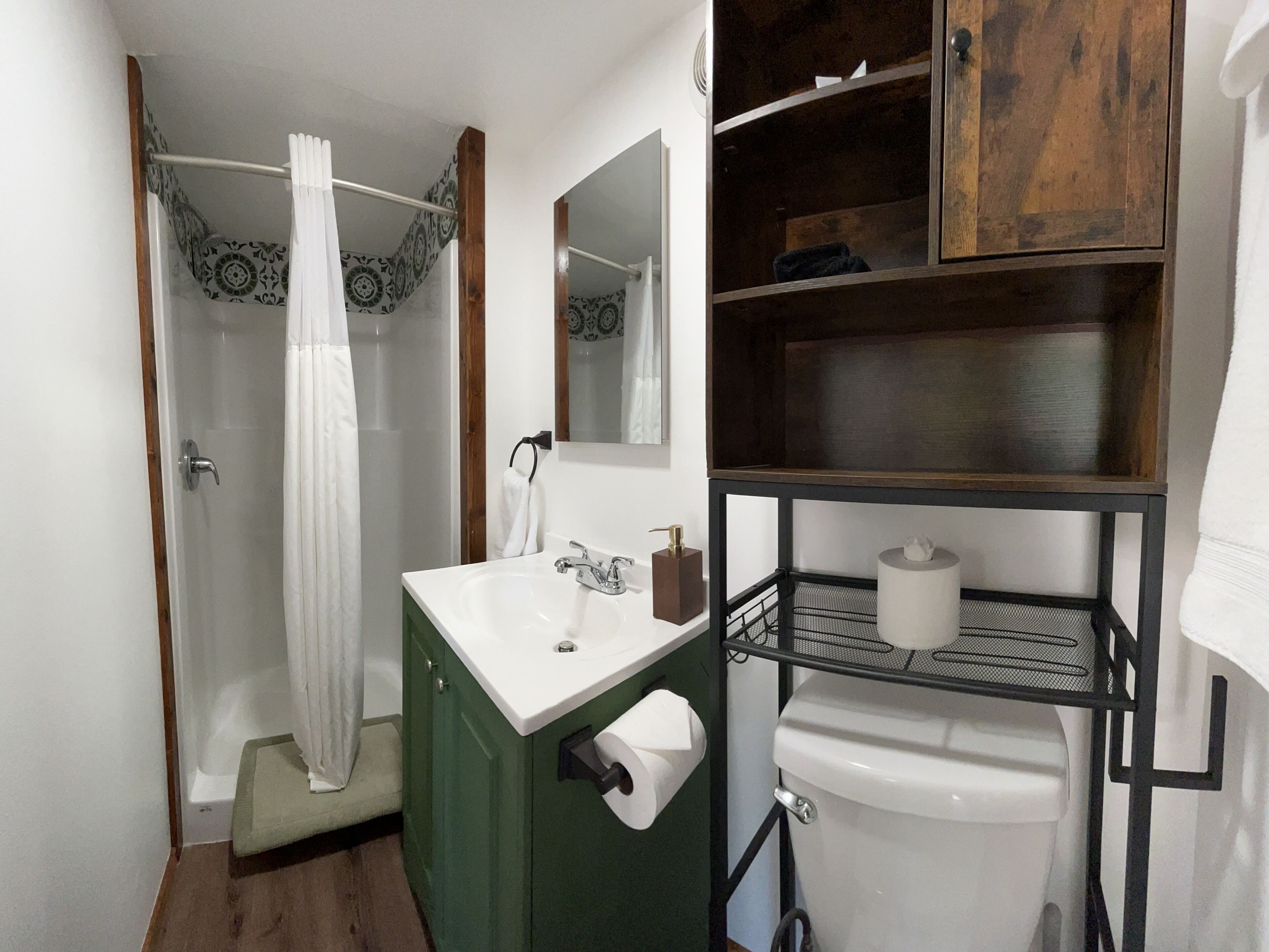 A bathroom with a shower, a sink, a toilet, and a mirror.