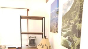 Una habitación pequeña con una cama, un escritorio con lámpara, un radiador y una ventana con persianas.