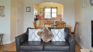 Una sala de estar con un sofá de cuero, una mesa de centro de madera y un comedor con mesa y sillas de madera.