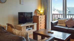 Una sala de estar con televisor, mueble de madera y sofá.