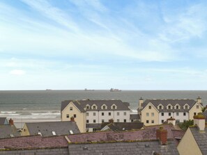A coastal town with traditional houses, a view of the sea, and ships in the distance. - Choose Ty Celyn for its great location just a short walk from the beach. (Broad Haven)