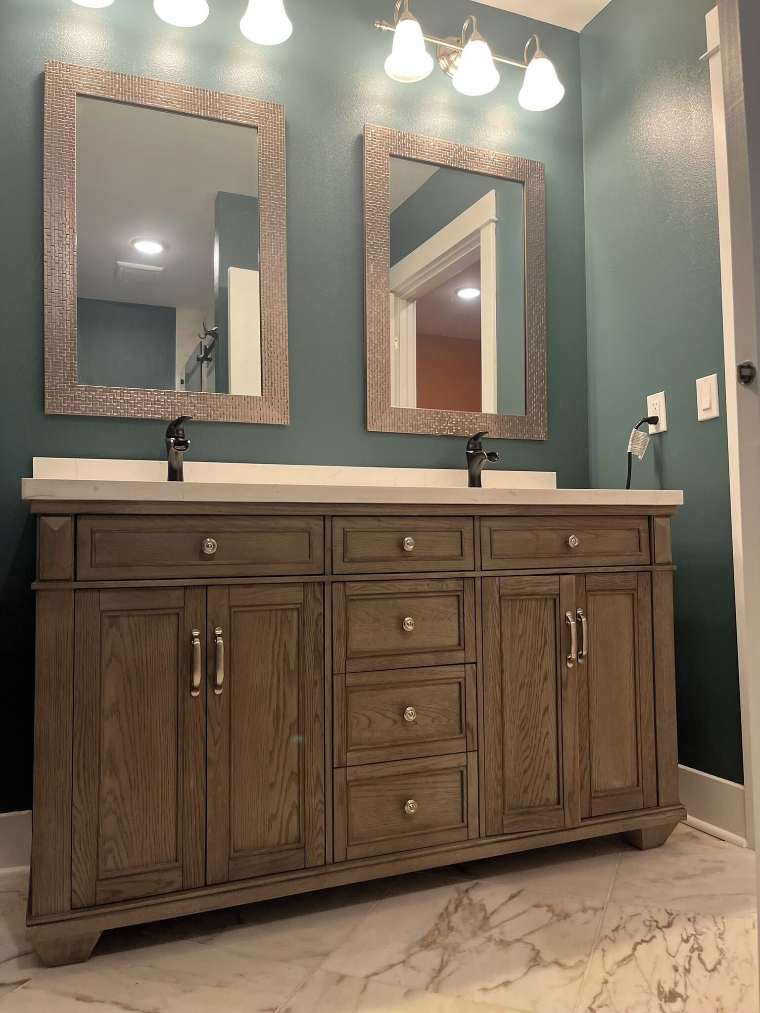 Une salle de bain avec deux miroirs, un meuble-lavabo en bois et un sol en marbre.