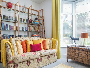 A cozy living room with a sofa, bookshelves, a globe, and a telescope.
