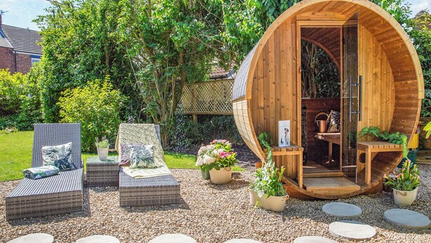 A wooden structure with a curved entrance, surrounded by a garden with potted plants and a seating area with wicker furniture. - 4 bedroom accommodation in Coxhoe, nearby Durham (Coxhoe, nearby Durham)