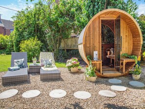 A wooden structure with a curved entrance, surrounded by a garden with potted plants and a seating area with wicker furniture. - 4 bedroom accommodation in Coxhoe, nearby Durham (Coxhoe, nearby Durham)