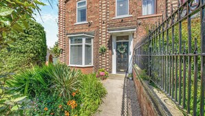 A brick house with a front garden, a black metal fence, and a door with a wreath. - 4 bedroom accommodation in Coxhoe, nearby Durham (Coxhoe, nearby Durham)
