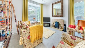 A living room with a sofa, a fireplace, a television, and a bookshelf. - 4 bedroom accommodation in Coxhoe, nearby Durham (Coxhoe, nearby Durham)